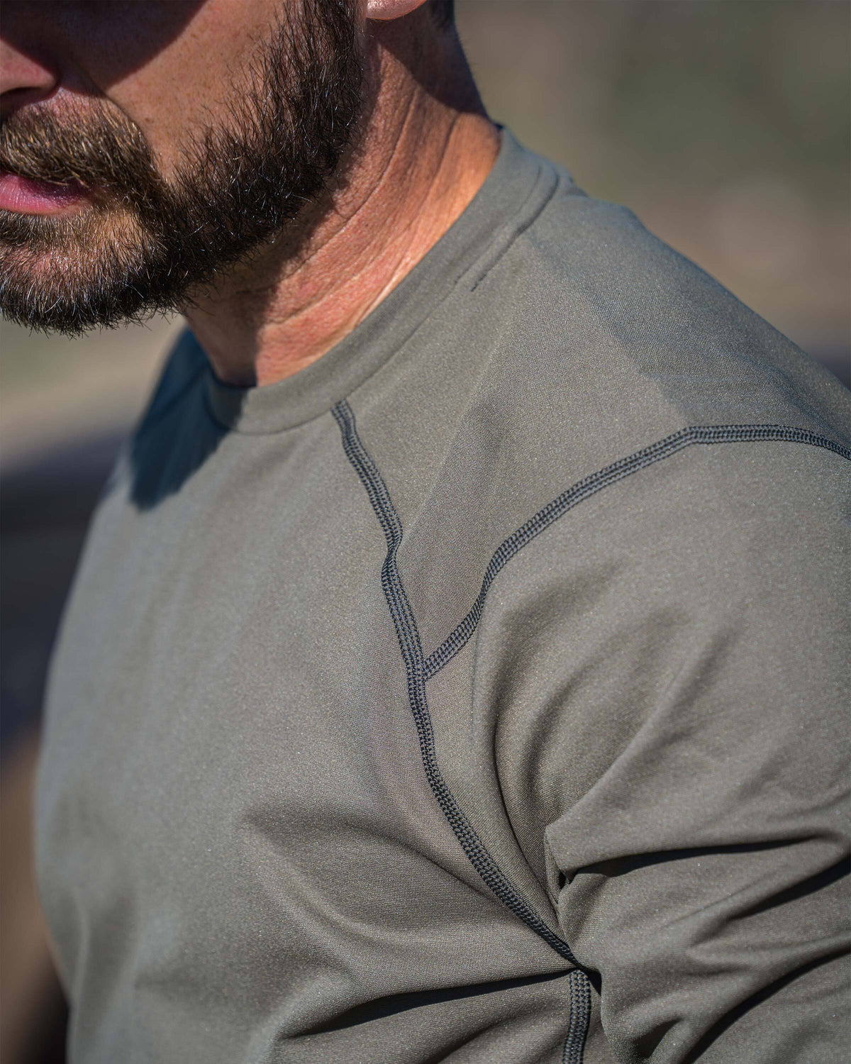 Close-up of man wearing Vital S3 Long Sleeve in Ash, highlighting raglan sleeve, showing the fabric texture and shoulder seam details.