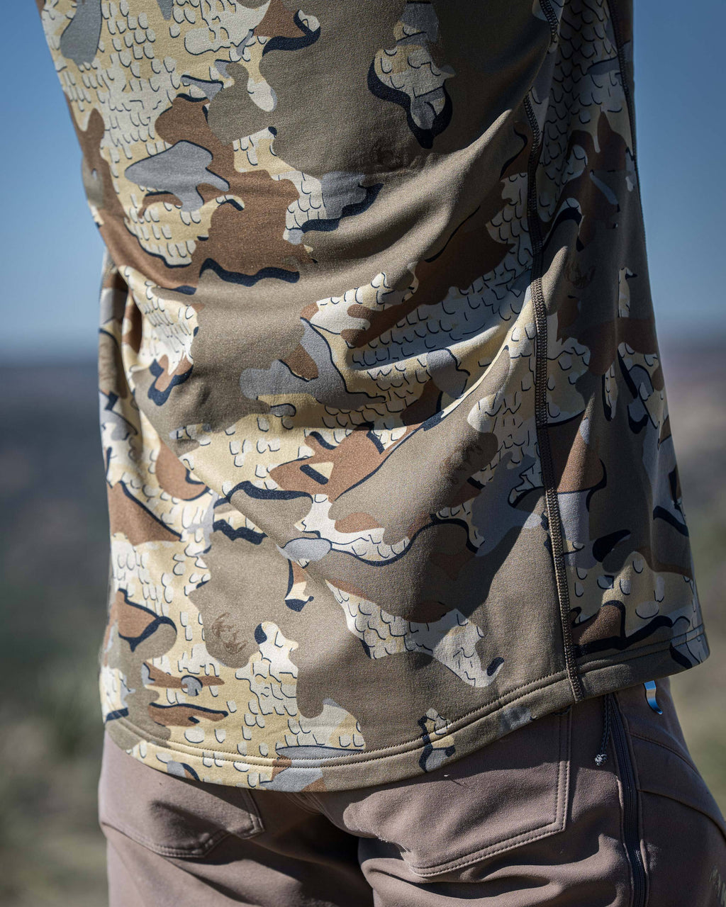 Close-up, back view of a person wearing a Vital S3 Long Sleeve Crew in Valo Camouflage, standing in an outdoor setting.