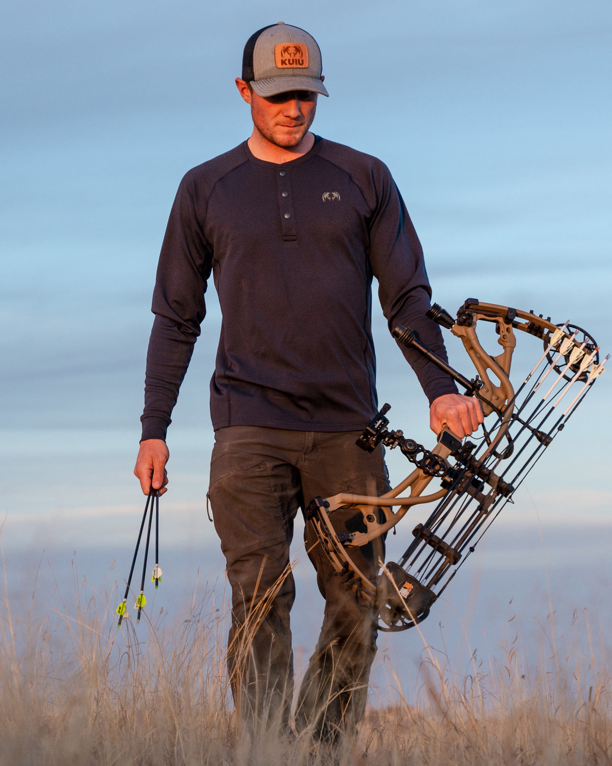 Front of Hunter Holding Bow Wearing Pro Merino 200 Henley in Steel Blue Color