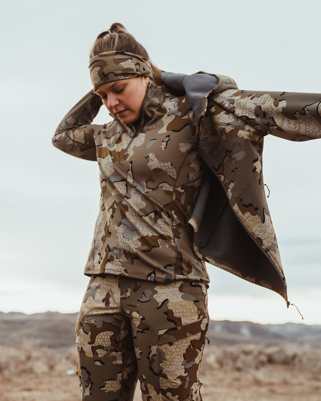 Angled, Front View of Hunter Putting on Peloton 240 Full Zip Hoodie in Valo Camouflage
