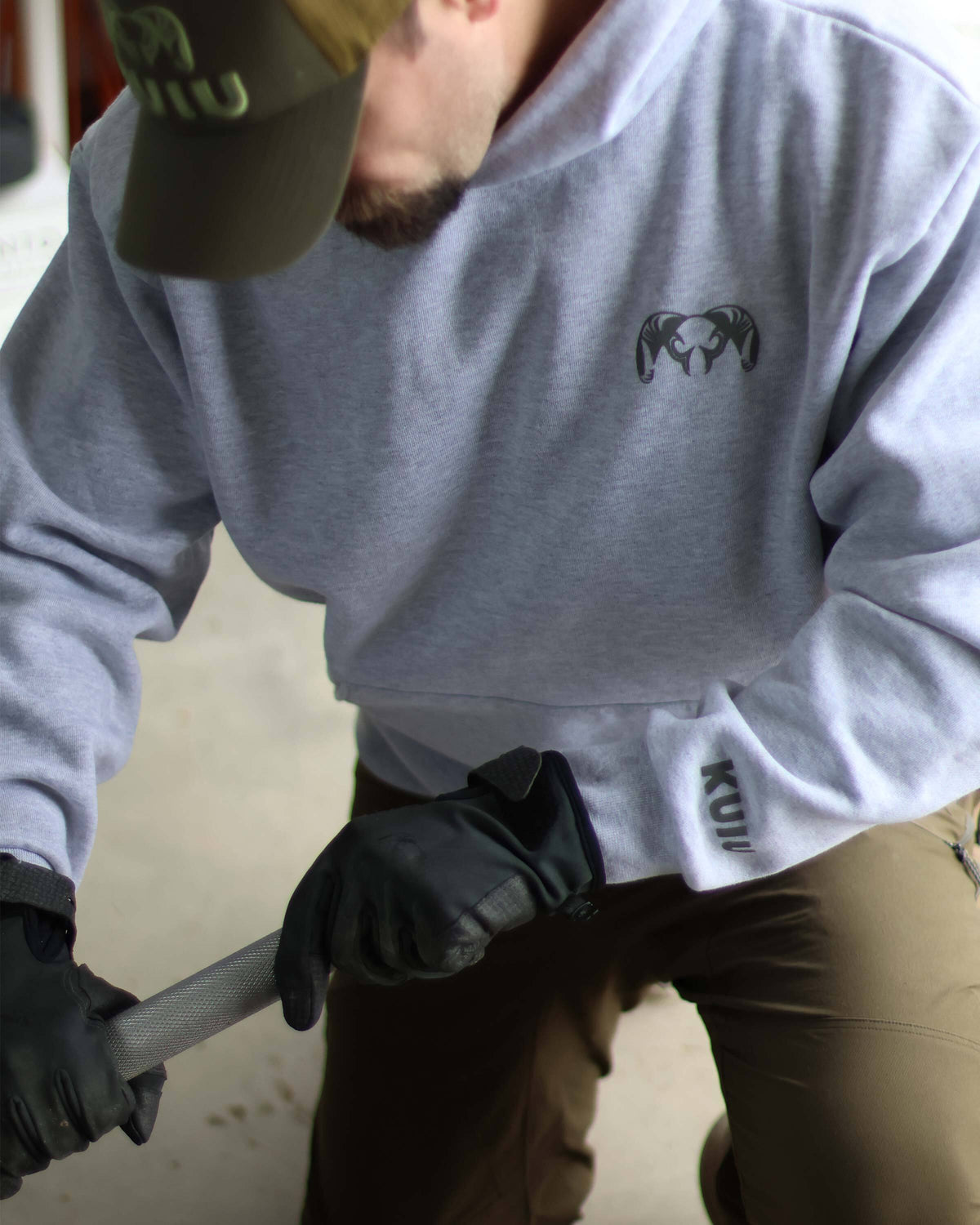Close-up of a man kneeling on one knee, wearing a Workgrade Heavyweight Hoodie in Heather Grey.