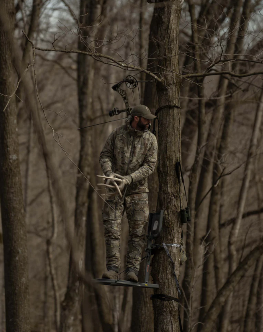 Hunter in a tree stand creating noise with deer antlers wearing KUIU Proximity Insulated Pant in Valo Camouflage