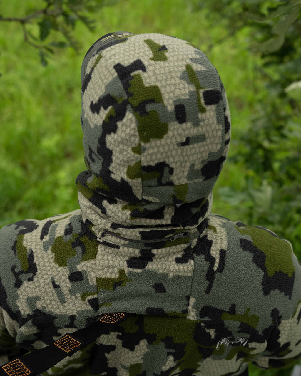 Back of Hunter in Treestand Wearing Proximity Hooded Insulated Jacket in Verde Camouflage Highlighting Treestand Safety Harness Port and Zip-off hood with magnetic connection points