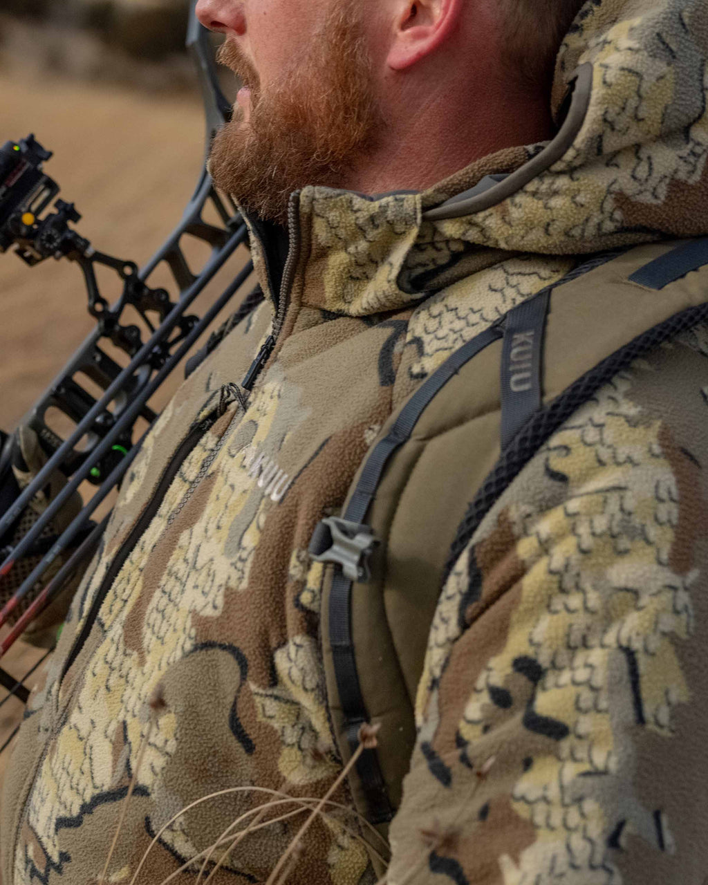 Side of Hunter Holding Bow Wearing Proximity Hooded Insulated Jacket in Valo Camouflage