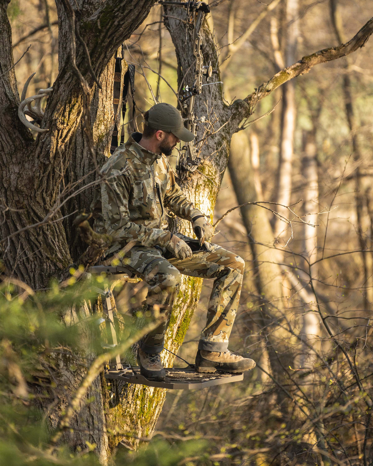 Hunter seated in treestand wearing Encounter Pant in Valo Camouflage using the vertical cargo pocket for easy access while seated