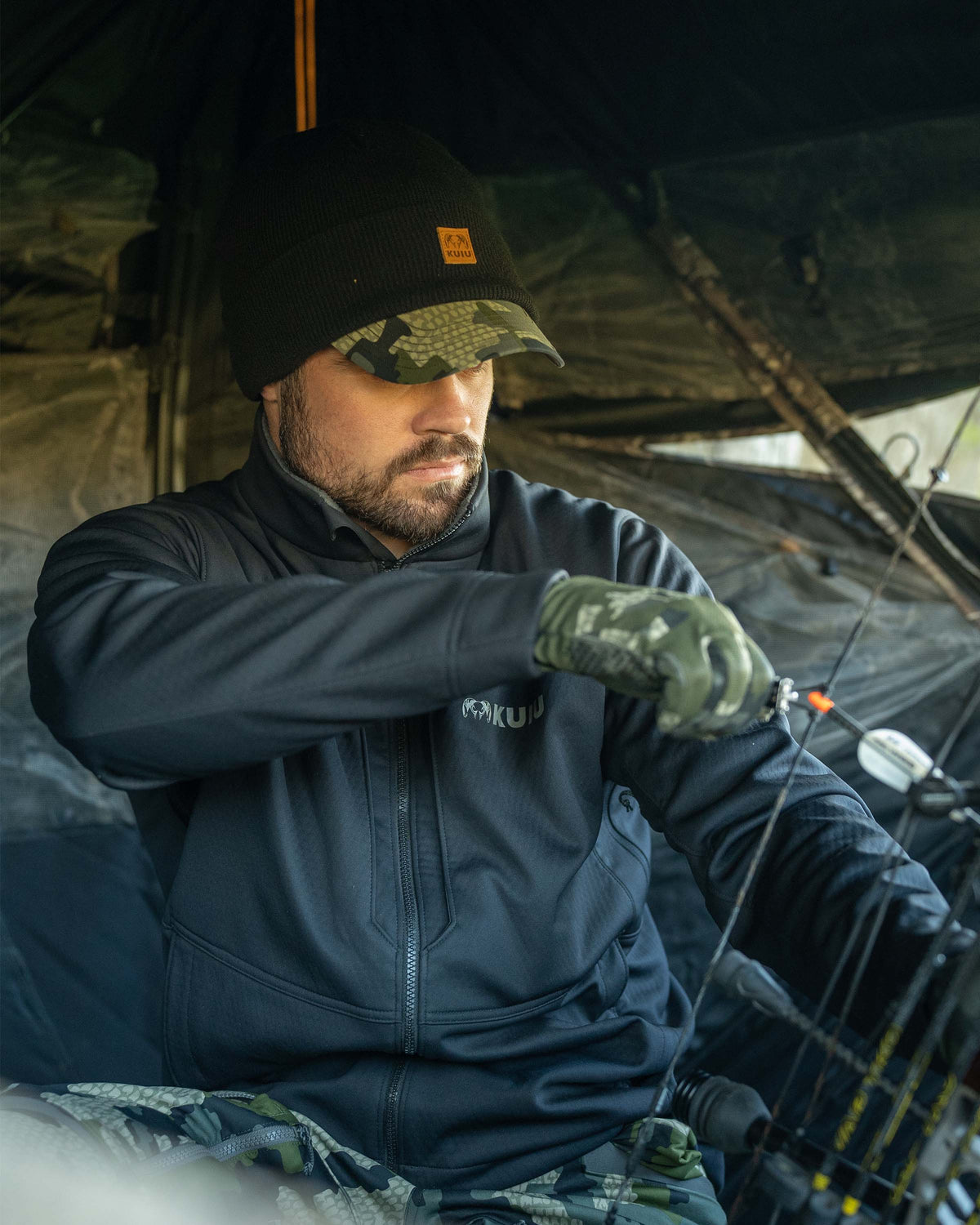 Hunter sitting in blind wearing Encounter Jacket in Black holding antlers