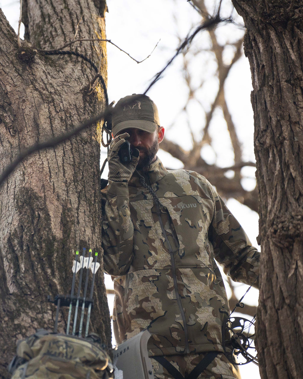 Hunter looking down using rangefinder wearing Encounter Jacket in Valo Camouflage