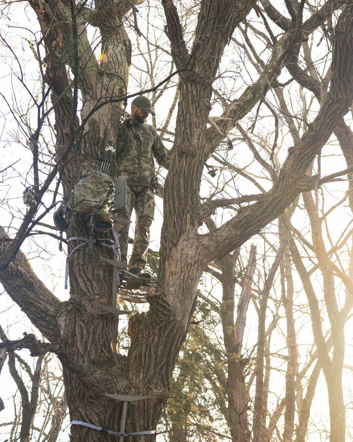 Zoomed out hunter looking down from treestand wearing Encounter Jacket in Valo Camouflage