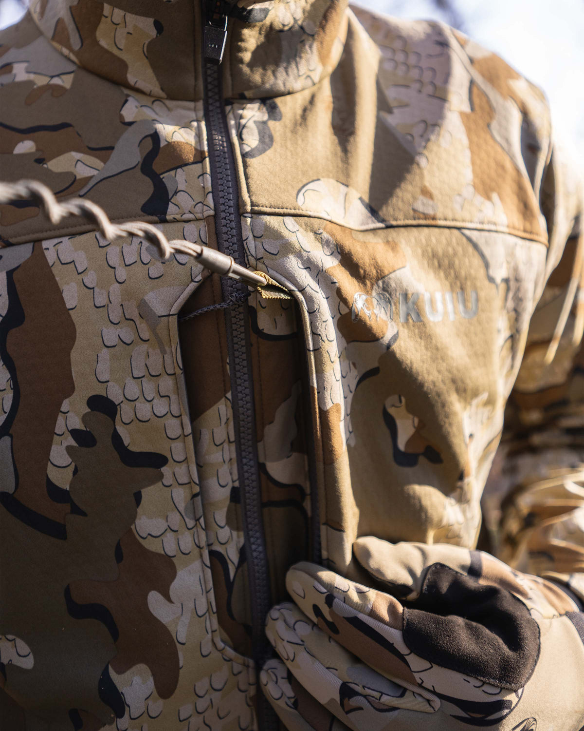Detail hunter wearing Encounter Jacket in Valo Camouflage using one of the dual chest pockets with interior accessory loop