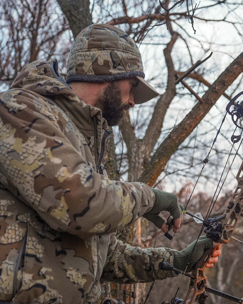 hunter with bow ready wearing Proximity Beanie in Valo Camouflage over hat