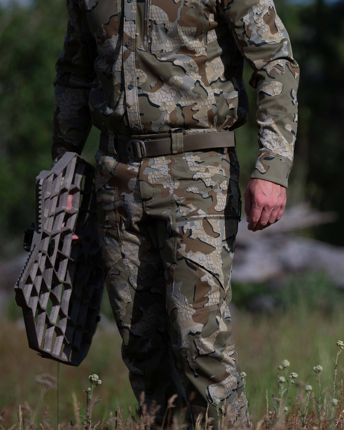 Close view of Hunter carrying an aluminum treestand, wearing Encounter LT Pant in Valo Camouflage 