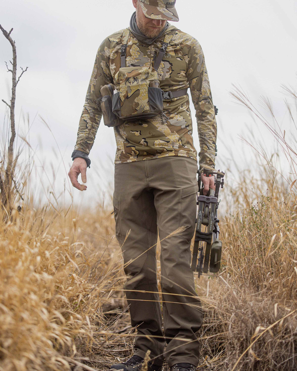 Front of Kevin Wilkey Holding Bow Wearing Attack Pants in Ash Brown Color