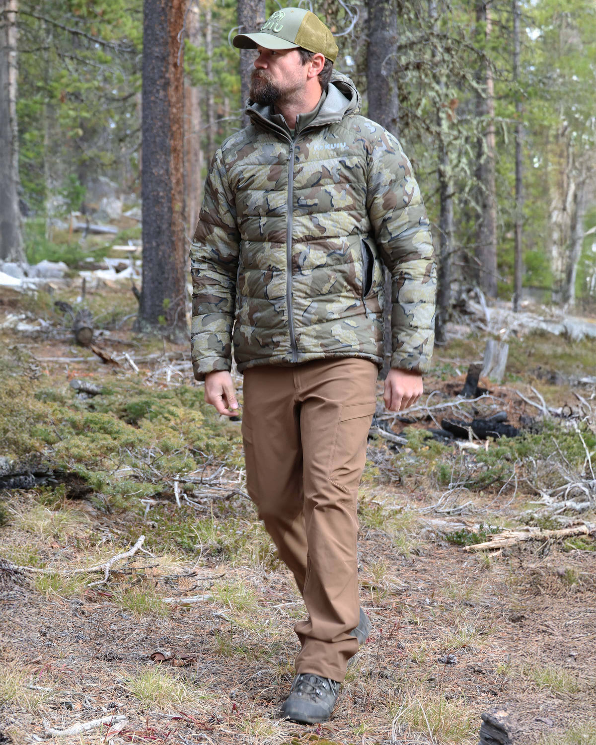 Hunter hiking through a forrest wearing Attack Pant in Grizzly Brown