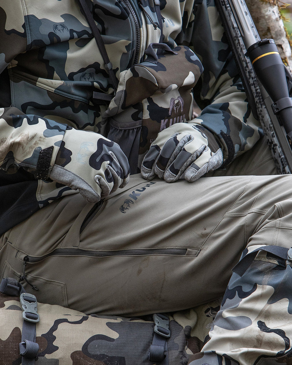 Front, Angled View of Hunter Wearing Attack Pants in Khaki Color Highlighting YKK Zippered Cargo Pocket and Hip Vent