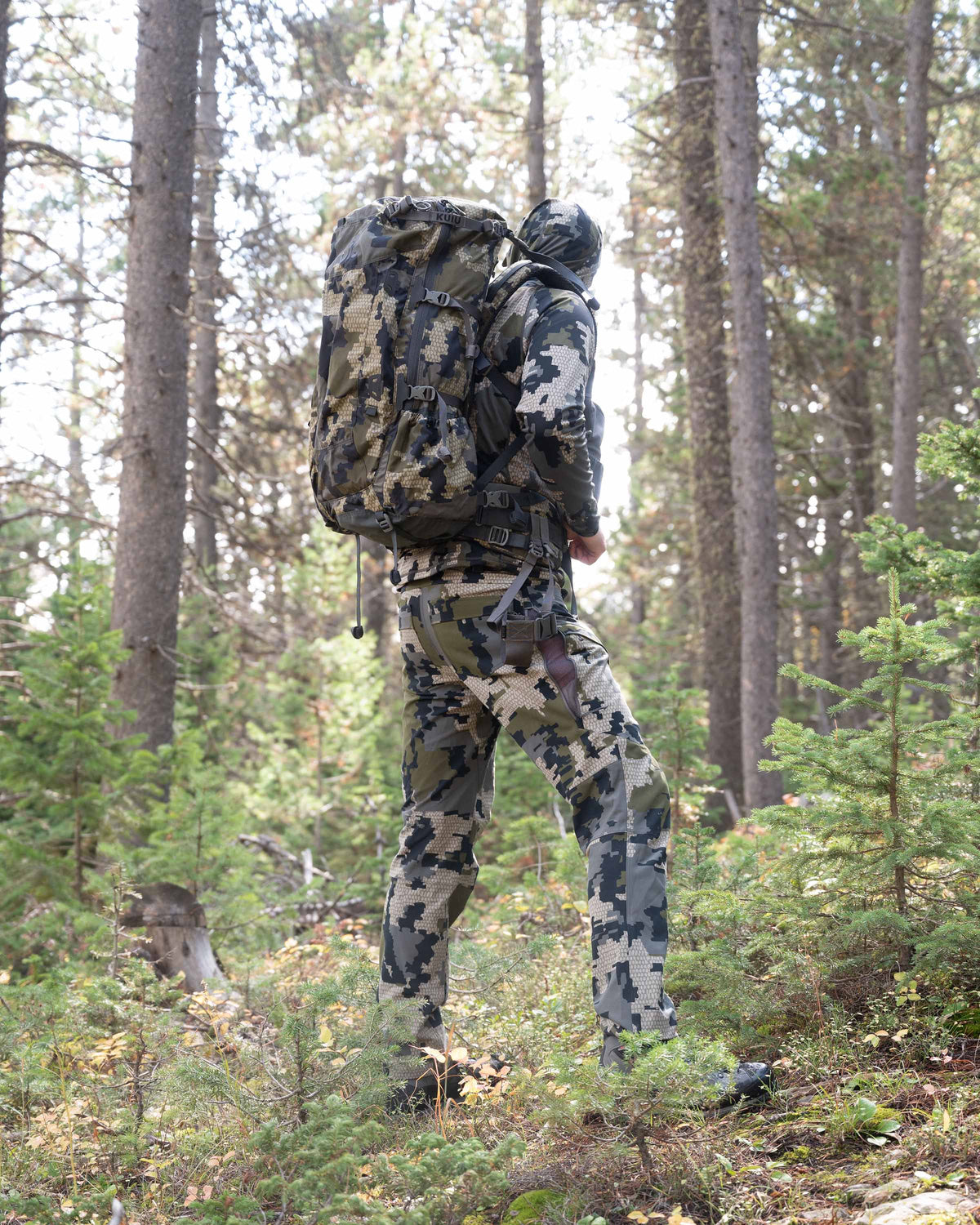 Side of Hunter Standing in Green Forest Wearing Attack Pants in Verde Camouflage Highlighting Open YKK Zippered Hip Vent