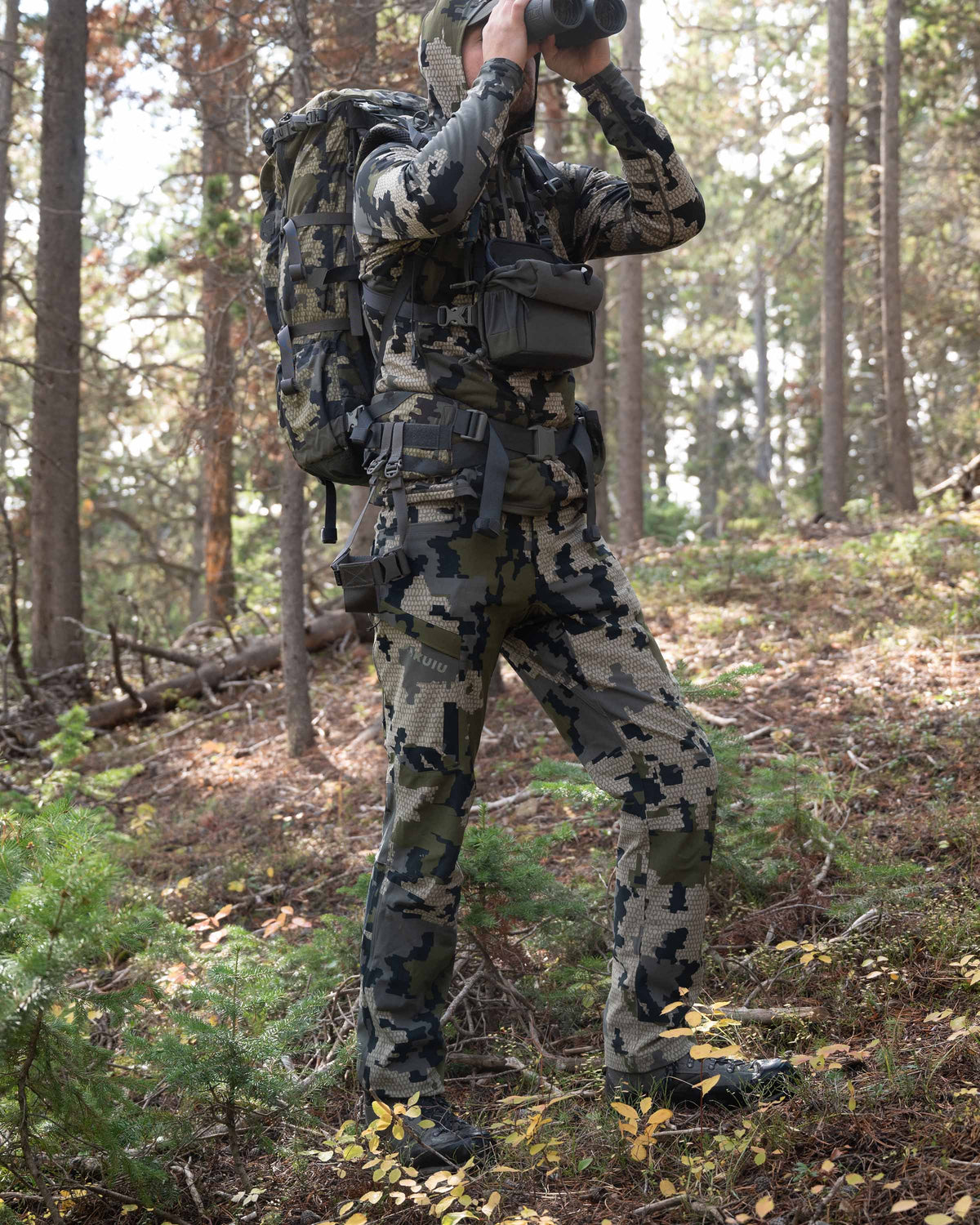 Angled, Front View of Hunter Standing in Green Forest Glassing Game Wearing Attack Pants in Verde Camouflage