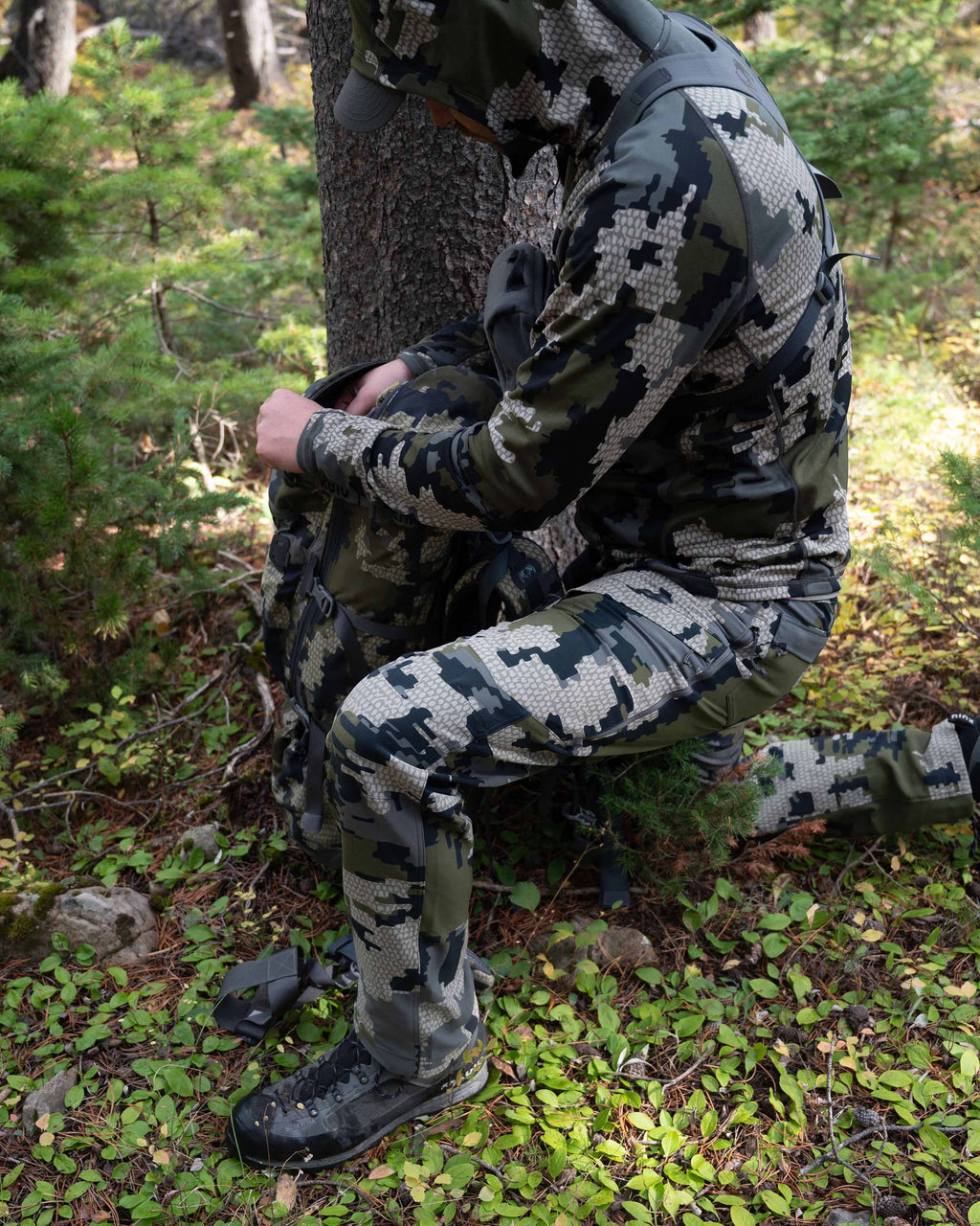 Side of Hunter Kneeling in Green Forest Wearing Attack Pants in Verde Camouflage Highlighting Articulated Knees