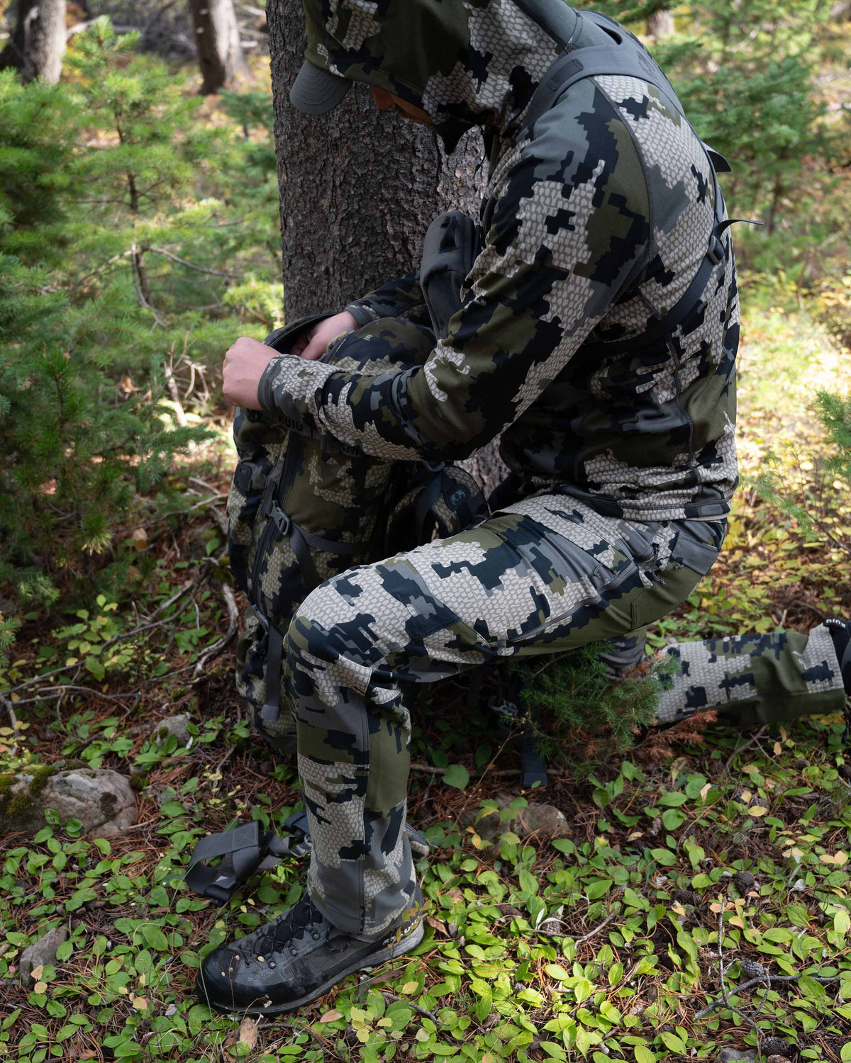 Side of Hunter Kneeling in Green Forest Wearing Attack Pants in Verde Camouflage Highlighting Articulated Knees