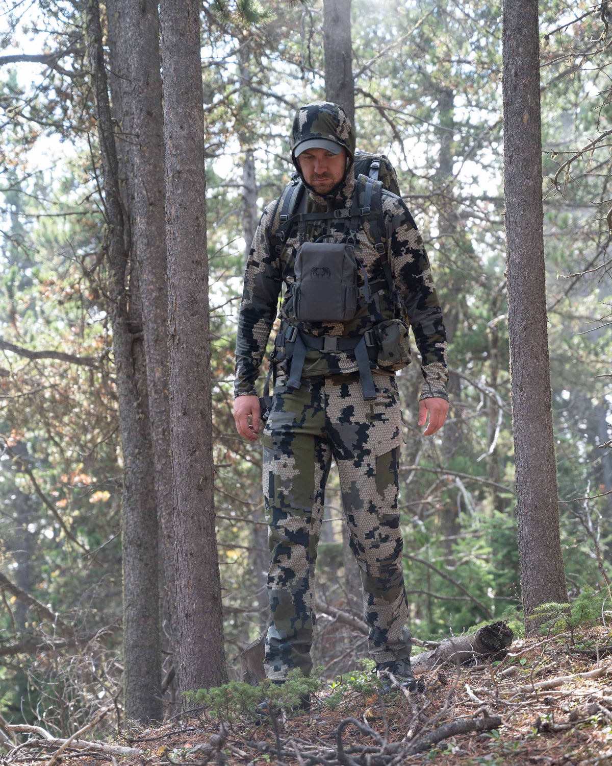 Front of Hunter Hiking in Green Forest Wearing Attack Pants in Verde Camouflage