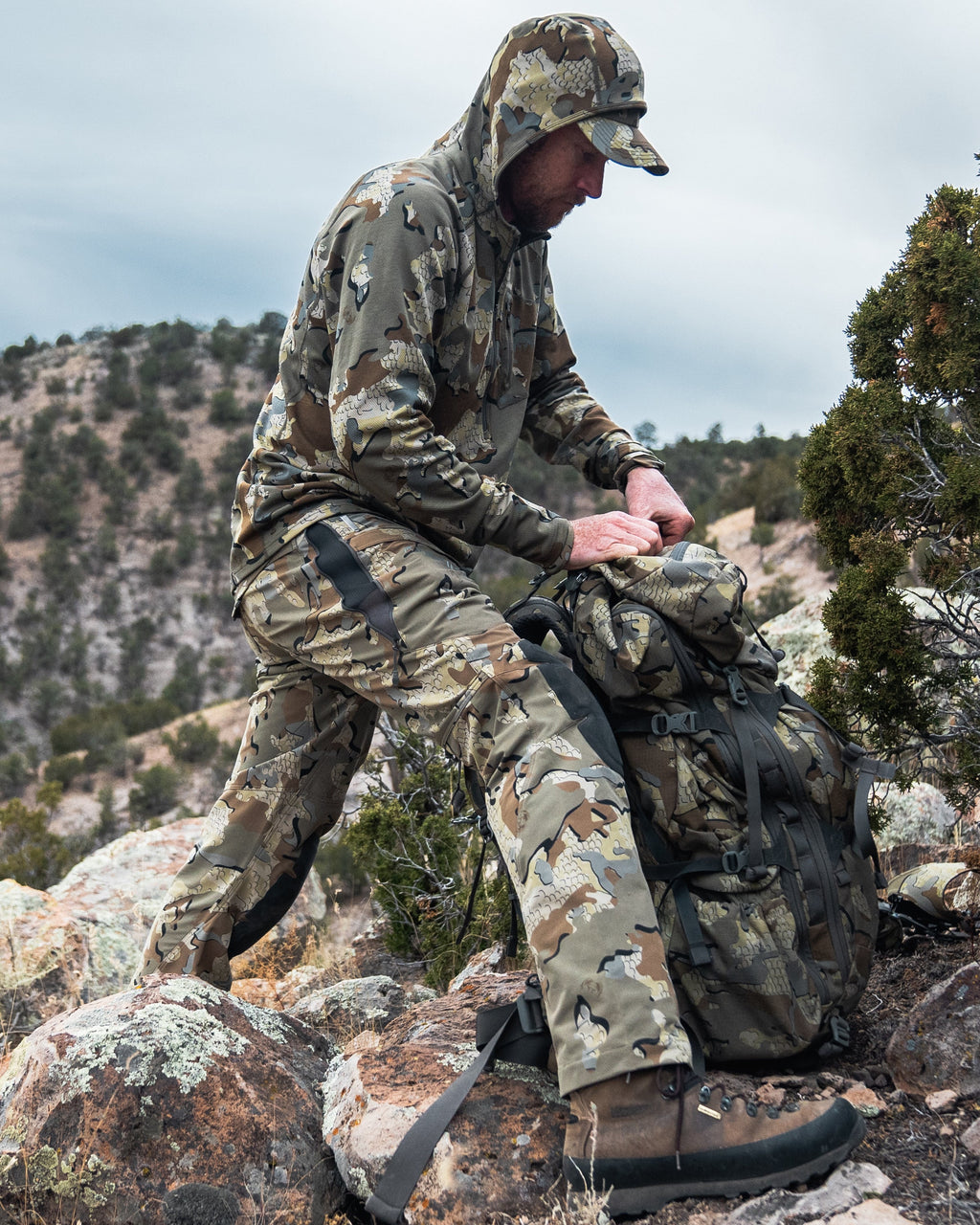 Side of Hunter Wearing Talus Hybrid Pants in Valo Camouflage Highlighting YKK Zippered Hip Vent