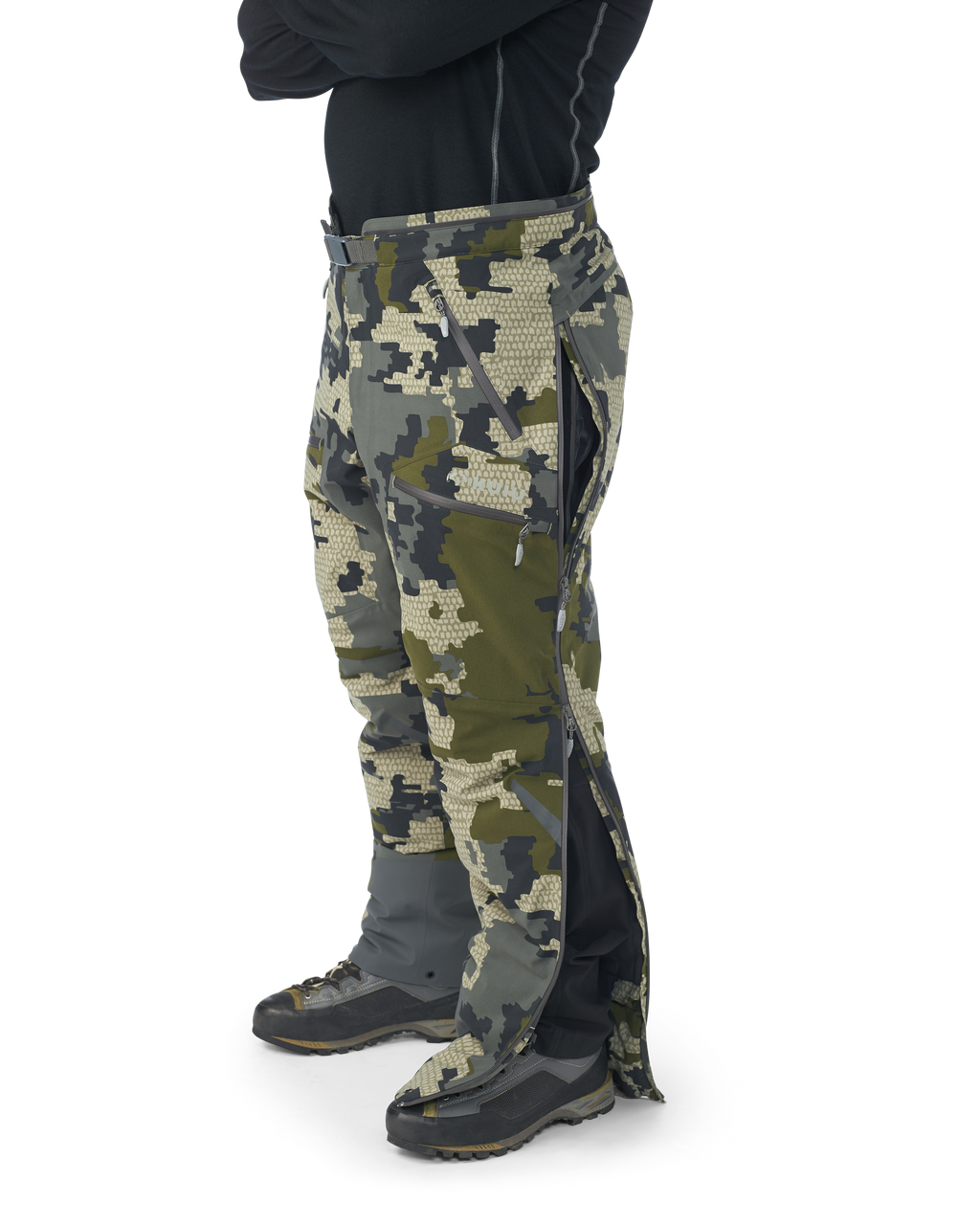 Hunter wearing Kutana Gale Force Pant in Verde Camouflage without suspenders over shoulders showcasing side leg zippers