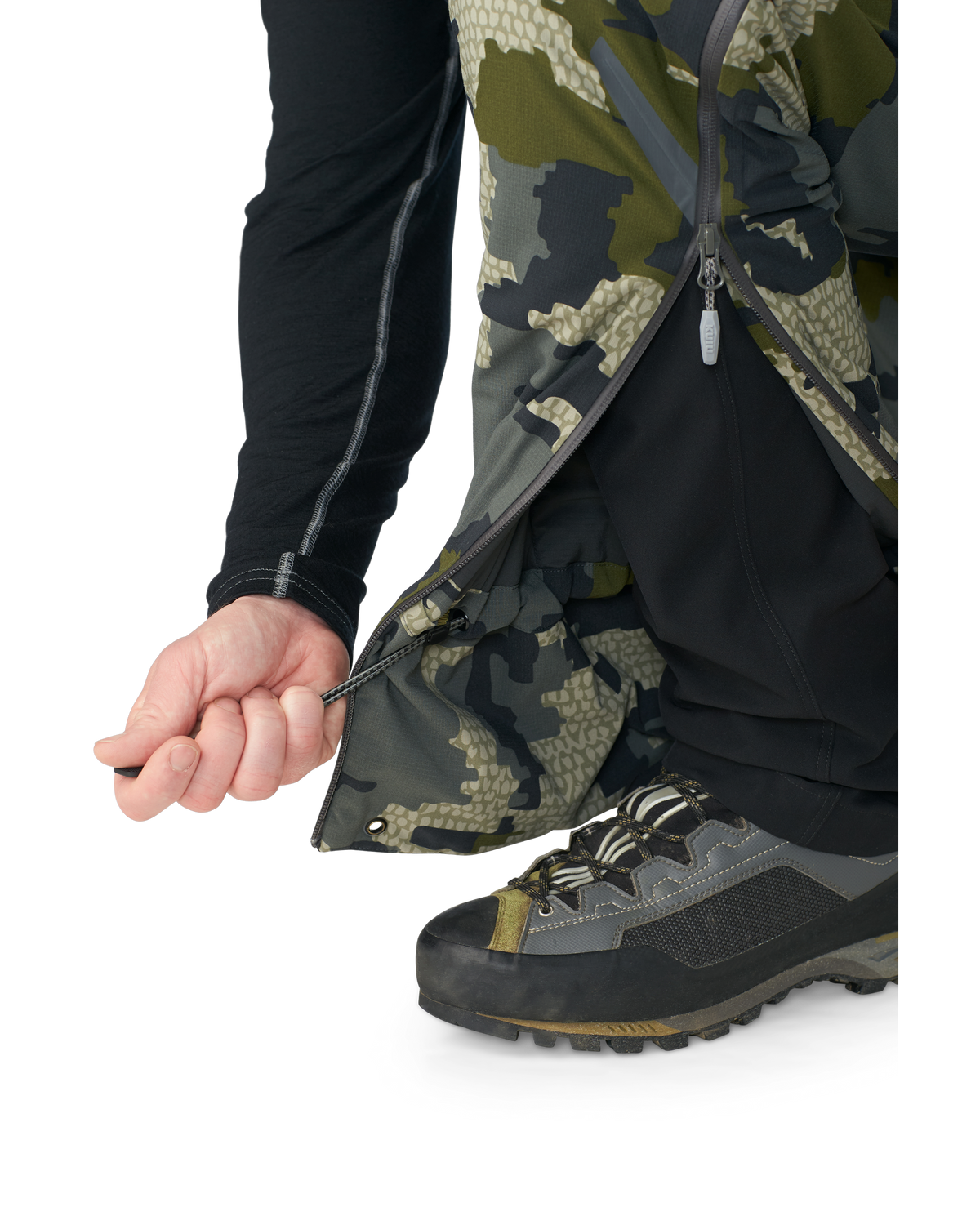Hunter wearing Kutana Gale Force Pant in Verde Camouflage showcasing inner ankle cinch cord
