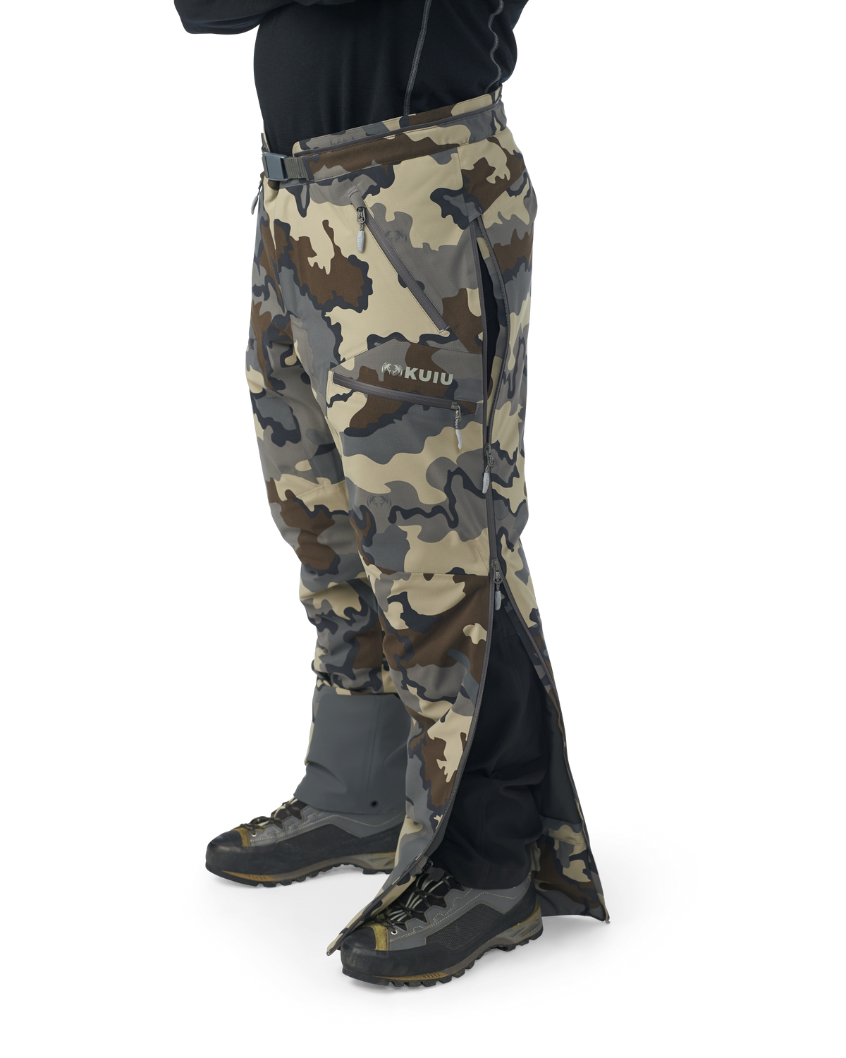 Hunter wearing Kutana Gale Force Pant in Vias Camouflage without suspenders over shoulders showcasing side leg zippers