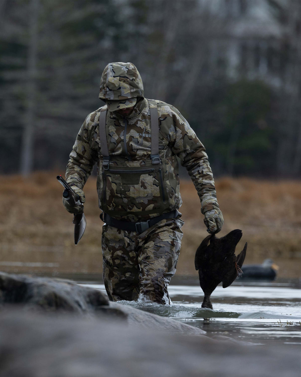 Hunter Wearing HD Flex Waders in Valo Camouflage Holding a Duck Walking Back to the Blind