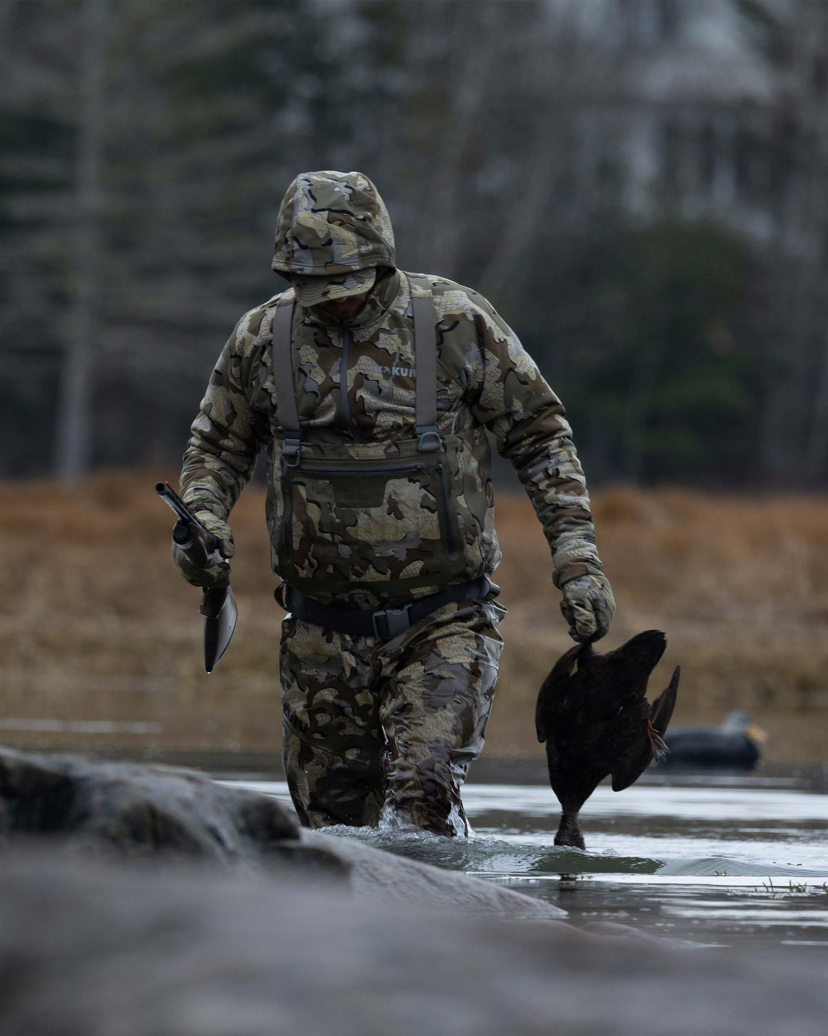 Hunter Wearing HD Flex Waders in Valo Camouflage Holding a Duck Walking Back to the Blind