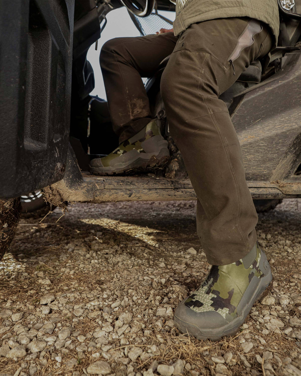 Side view of hunter sitting partially inside a UTV, wearing KUIU Ankle Boot in Verde Camouflage