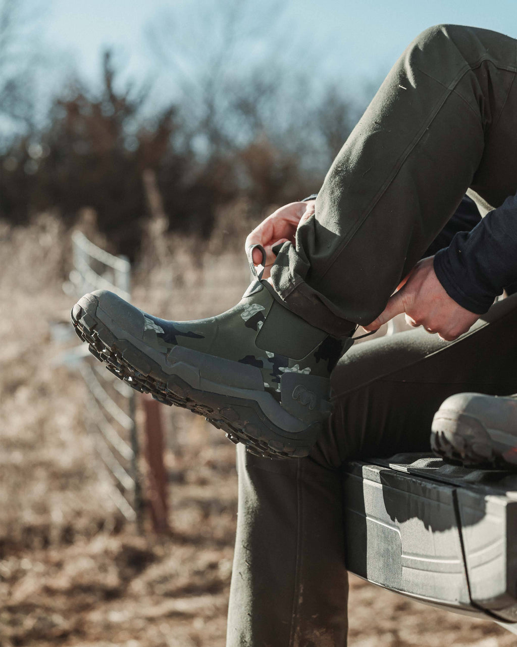 Close-up view of hunter utilizing the front pull-loops on the KUIU Ankle Mud Boot in Verde Camouflage