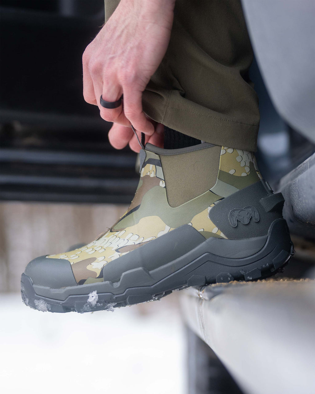 Close-up of Hunter using front pull-on loops on the KUIU Ankle Mud Boot in Valo Camouflage