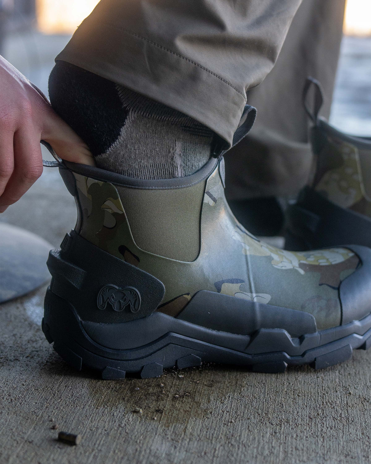 Close-up of hunter slipping his right foot into the KUIU Ankle Mud Boot in Valo Camouflage