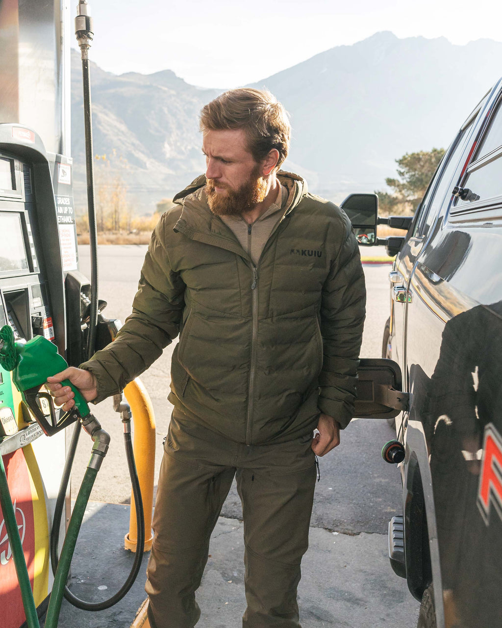 Hunter wearing Elements Hooded Jacket in Ash Brown reaching for the gas pump to fill his truck with fuel