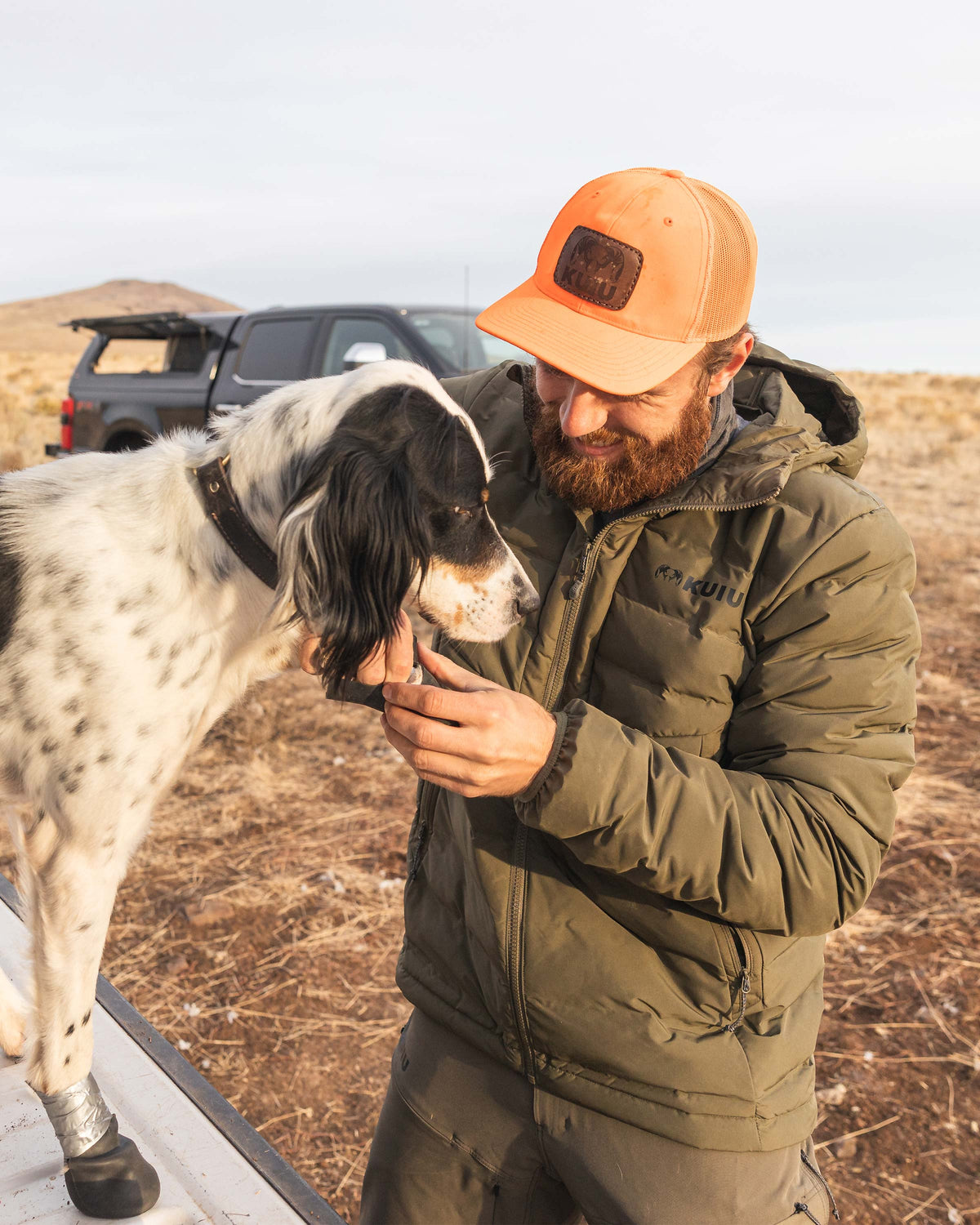 Hunter wearing Elements Jacket in Ash Brown smiling and petting his English Setter dog