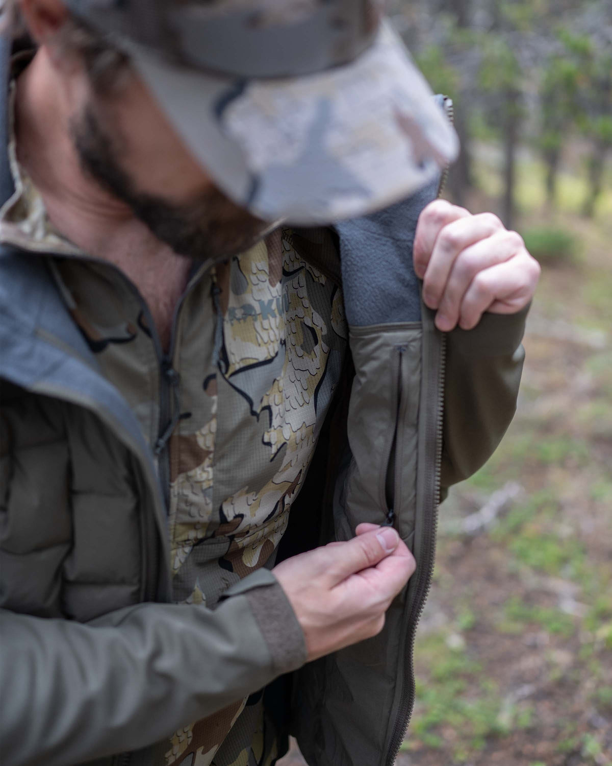 Hunter wearing Axis Thermal Hooded Jacket in Ash Brown using zippered interior pocket