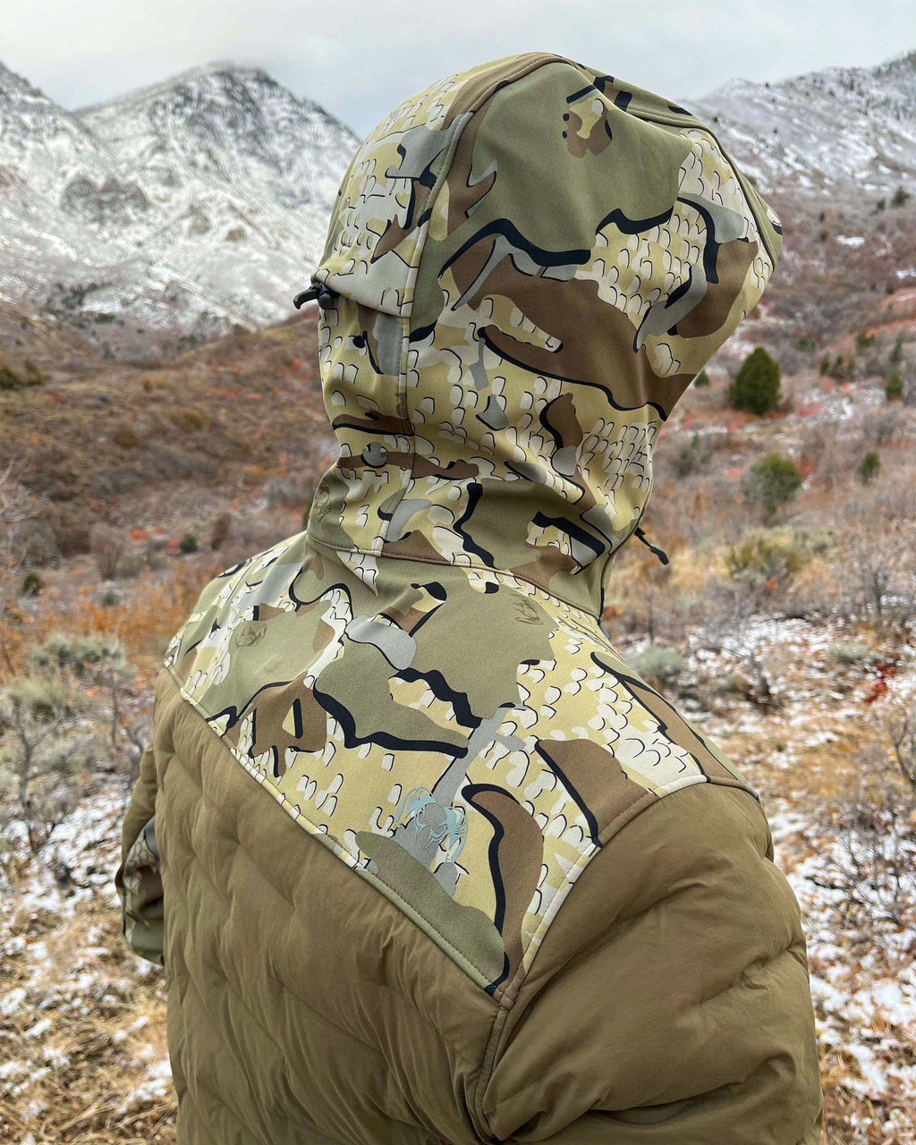 Rear, Angled View of Hunter Wearing Axis Thermal Hybrid Hooded Jacket in Valo Camouflage Highlighting Waterproof Paneling in Hood, Shoulders and Neck