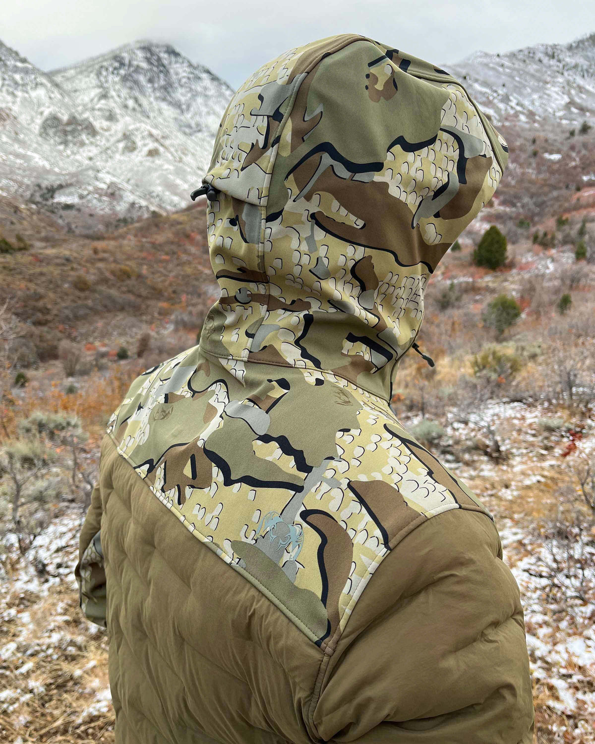Rear, Angled View of Hunter Wearing Axis Thermal Hybrid Hooded Jacket in Valo Camouflage Highlighting Waterproof Paneling in Hood, Shoulders and Neck