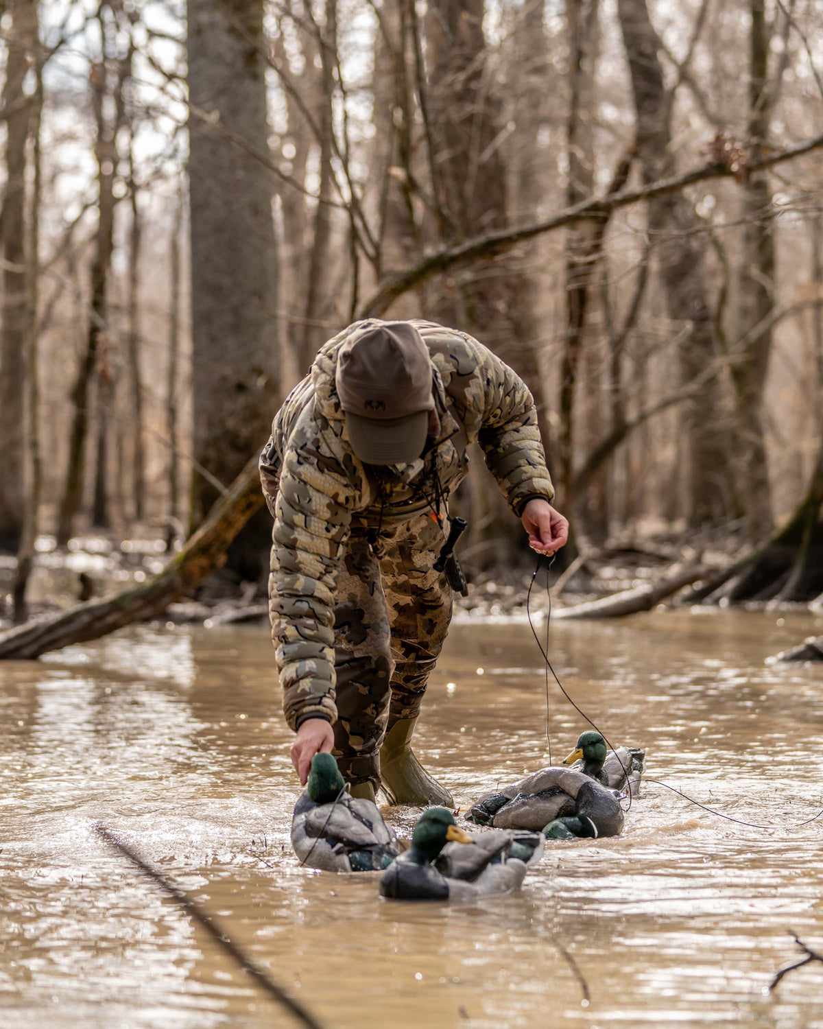 Hunter Wearing Flyway Insulated Hooded Jacket in Valo Camouflage Collecting Mallard Decoys in Flooded Timber