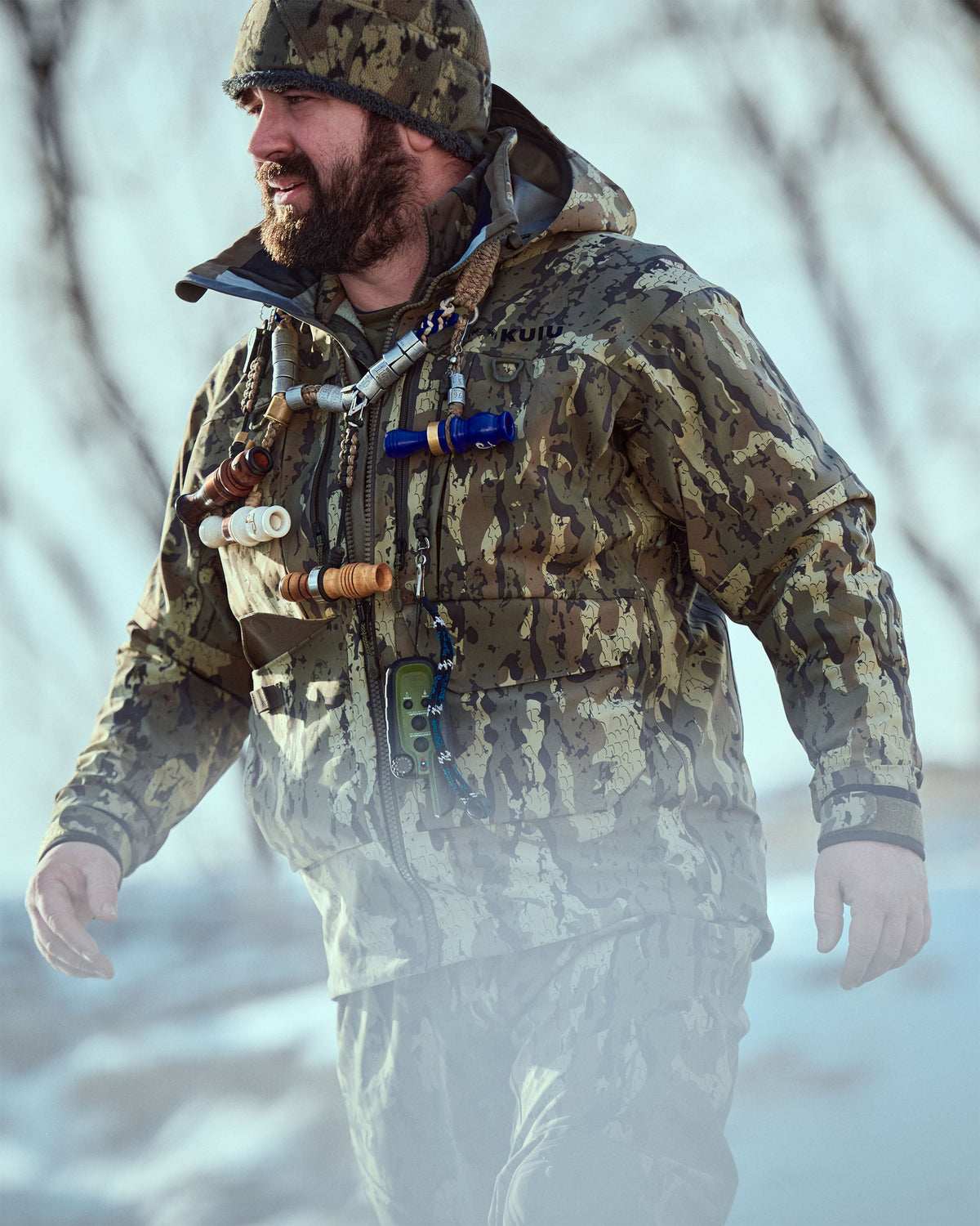 Hunter wearing a HD Flex Storm Shell Jacket in Veros Camouflage, standing outdoors in a cold and snowy environment. 