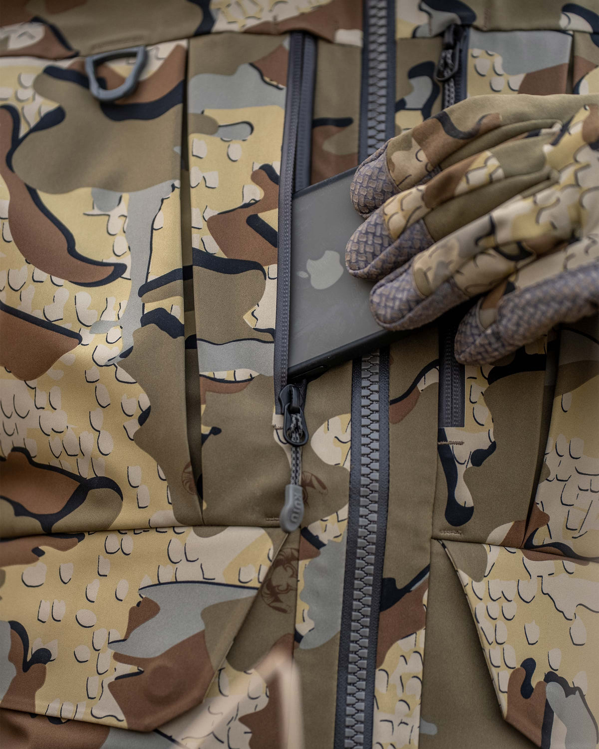 Detail phone being placed in zippered chest pocket on the HD Flex Storm Shell Jacket in Valo Camouflage