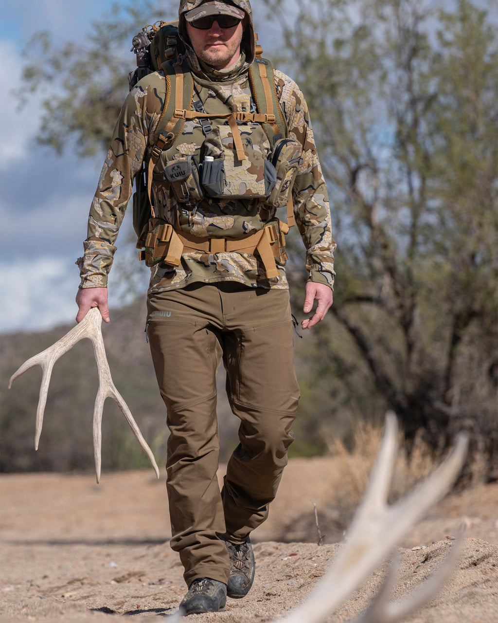 Hunter Wearing Pro Brush Pants in Bourbon Brown Walking in the Desert Holding Big Mule Deer Shed, Walking up to Another