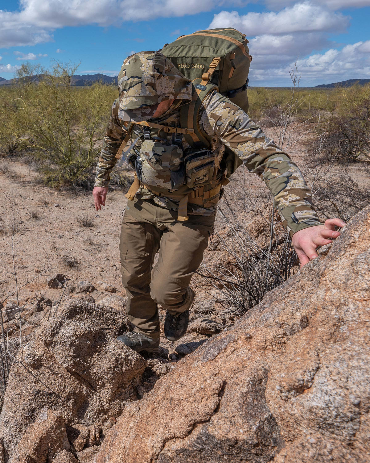 Hunter Walking in Rocky, Desert Terrain Wearing Pro Brush Pants in Bourbon Brown