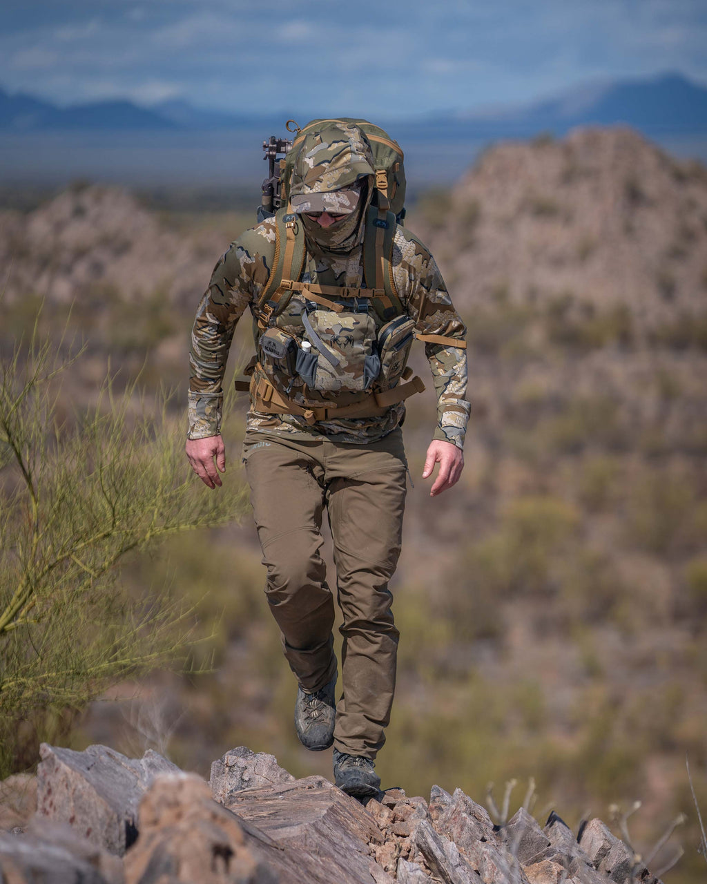 Hunter Walking on Ridge in the Desert Wearing Pro Brush Pants in Bourbon Brown