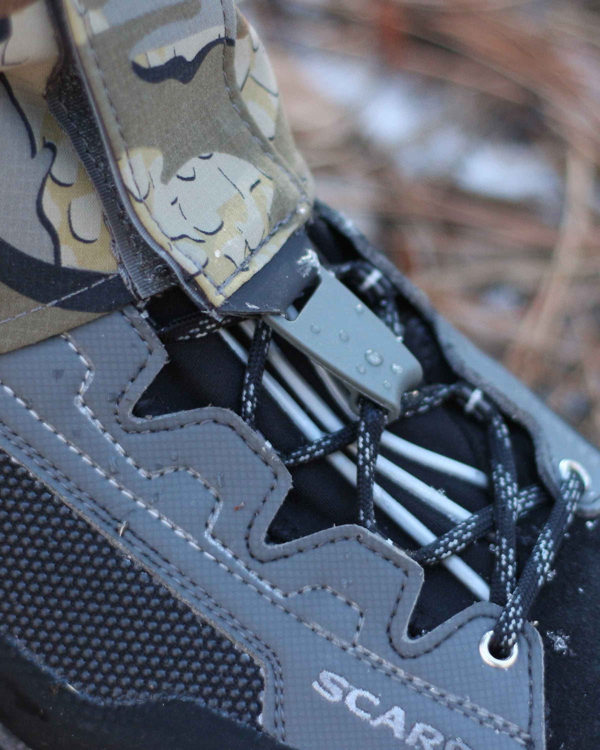 Kutana Storm Gaiter in Valo Camouflage hooked onto the lace of a boot