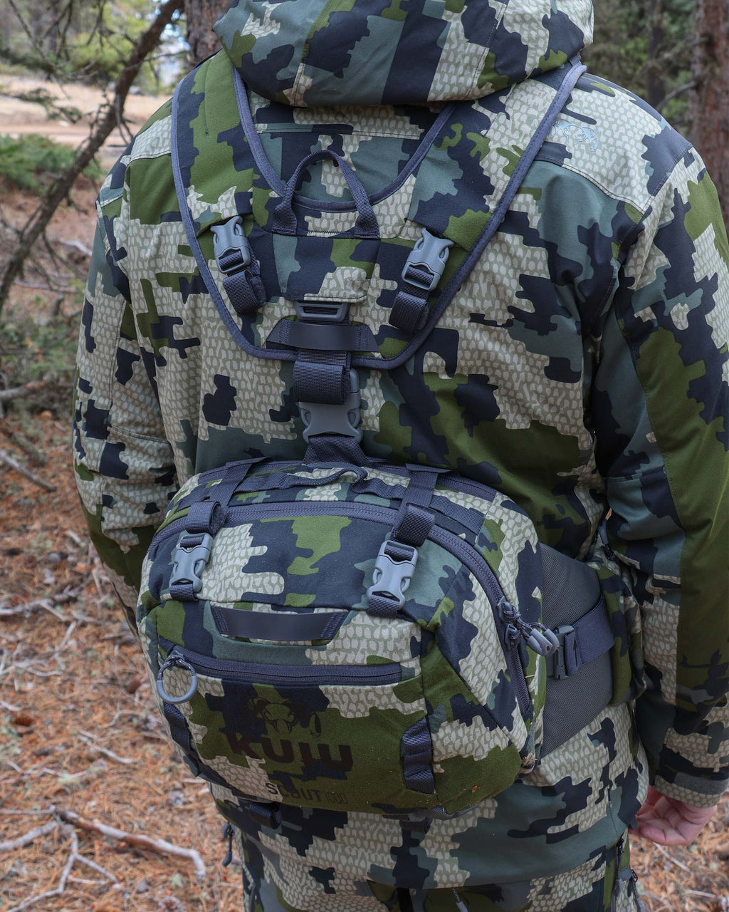 Rear view of hunter wearing the Scout 1000 in Verde, Featuring compression straps strategically placed on the front exterior, top, and bottom, alongside the integrated harness system