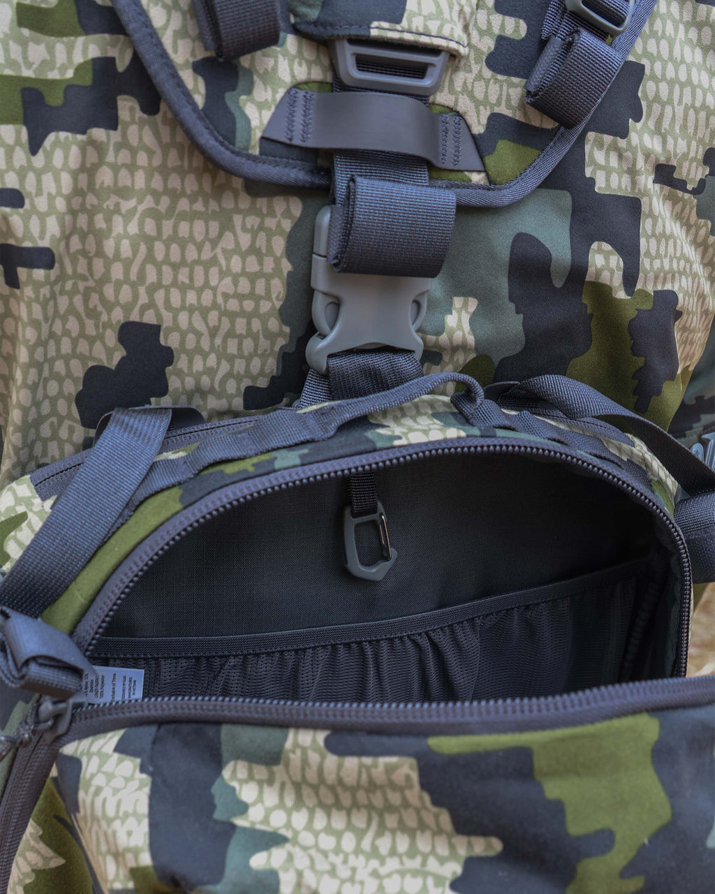 Close-up of unzipped main compartment, highlighting internal stretch mesh drop pocket 