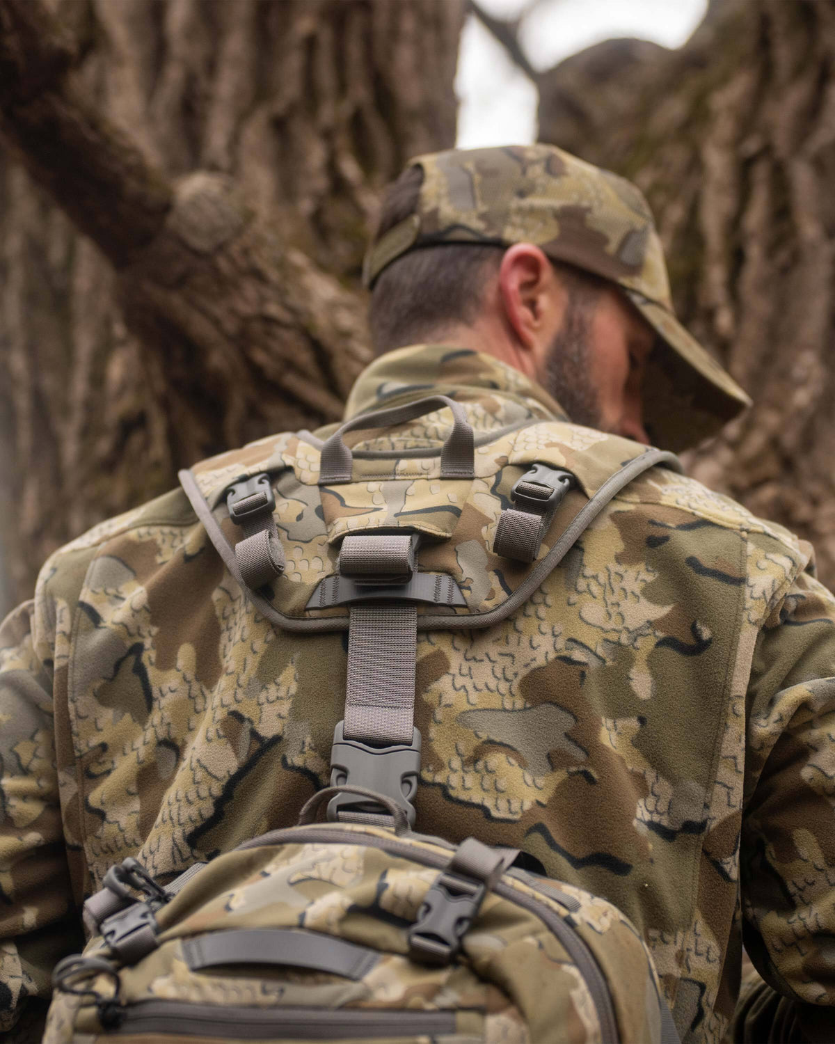 Whitetail hunter in treestand wearing KUIU Valo camo and Scout 1000 waist pack with shoulder straps