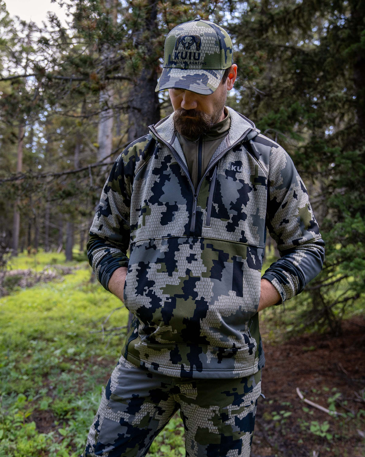 Hunter using the zippered pass-thru hand pockets on StrongFleece 235 Zip-T Hoodie in Verde Camouflage