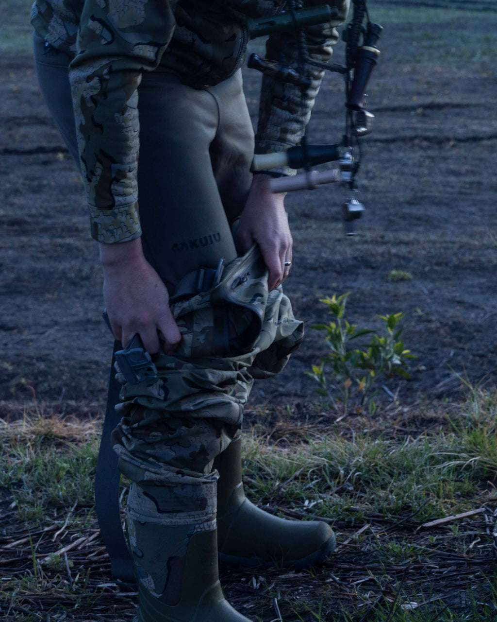 Hunter wearing StrongFleece 290 Layering Pant in Ash Brown underneath KUIU HD Flex Wader, side facing view